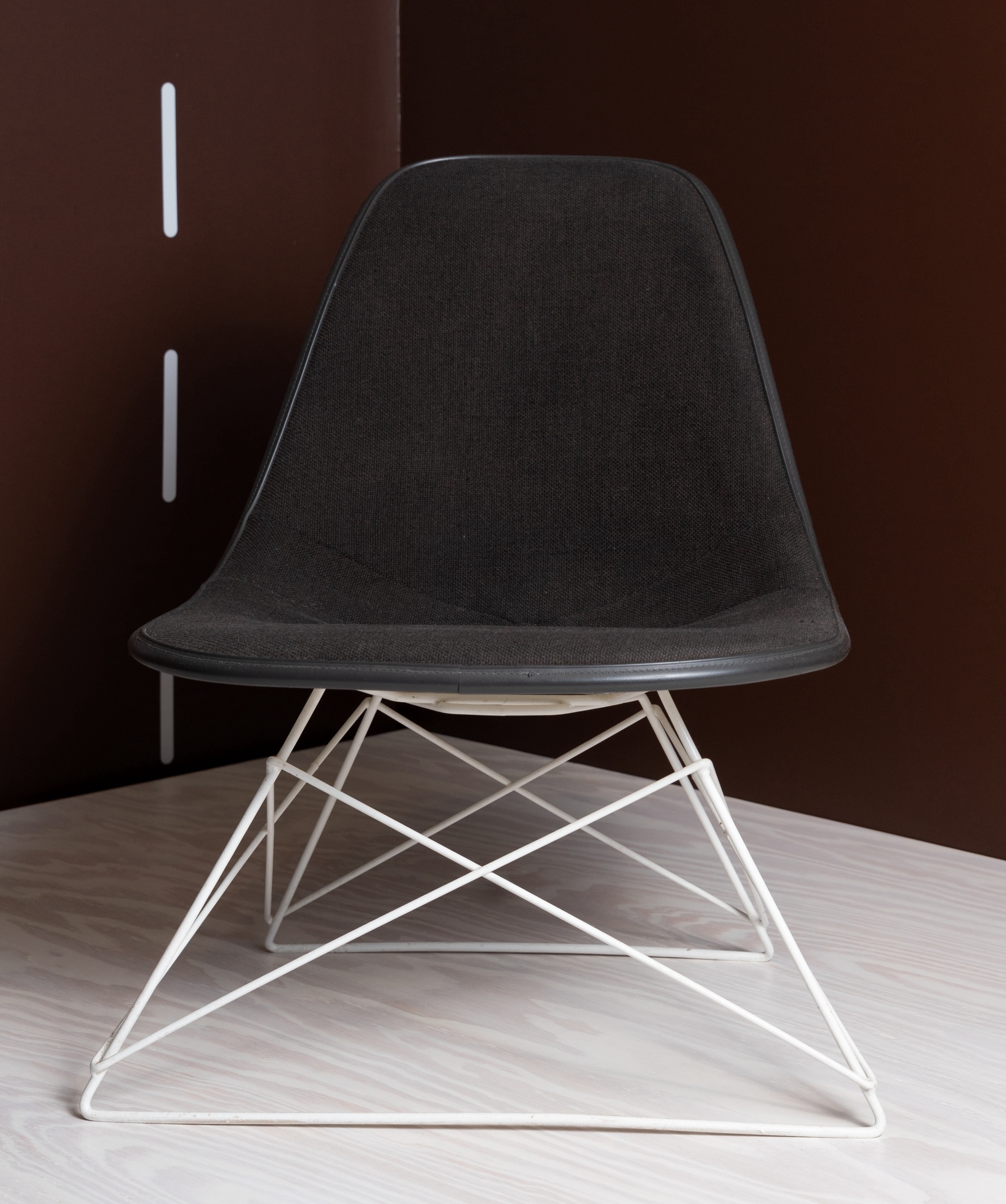 A black/dark gray upholstered side chair with a white metal base with a triangle and 'x' patterns to create its structure.